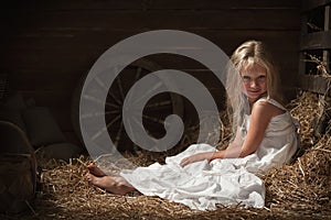 Girl sits on hay in the barn