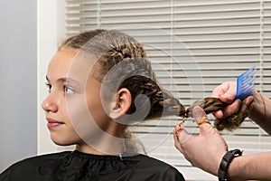 The girl sits at the master on hairdresses, does a stacking photo