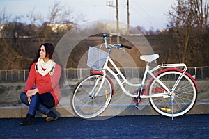 The girl sits next to a parked bike. Rest on the spring cycle