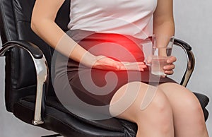 A girl sits in an office chair and holds a pill for pain in menstruation, business, close-up, anti-inflammatory