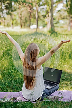 the girl sits outdoors and works at a laptop. she rejoices at the end of the working day. freelance. selfeducation. the photo