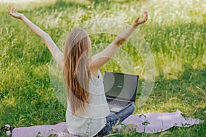 the girl sits outdoors and works at a laptop. she rejoices at the end of the working day. freelance. selfeducation. the photo