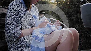 A girl sits on a park bench and rocks the baby