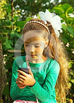 Girl sits in park and plays with cell phone