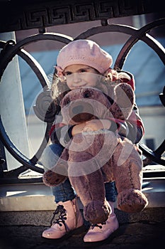 Girl sits at a pig-iron fencing of the bridge