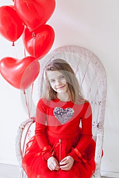 Beautiful girl sits with red heart balloons