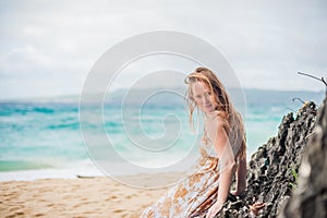 A girl sits on a rock on the beach of Boracay