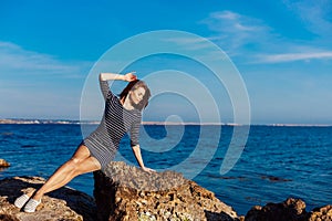 Girl sits on the rocky beach enjoys sunshine