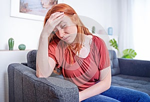 Girl sits on the sofa suffer chronic head pain
