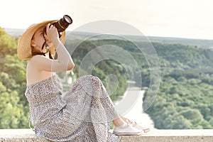 Girl sits and takes pictures against the background of forest and meandering river