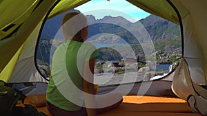 A girl sits in a tent and looks at the beautiful nature of Norway