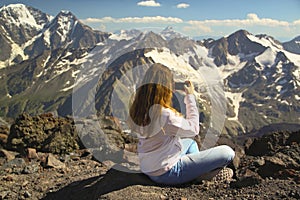 Girl sits on the top of the mountain and take pictures