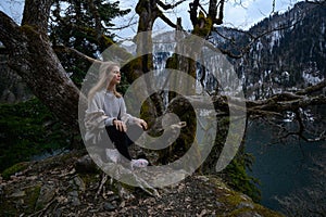 Girl sits on a tree and meditates near lake Ritsa in Abkhazia