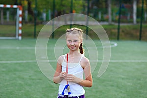 The girl sits on the twine on the sports ground