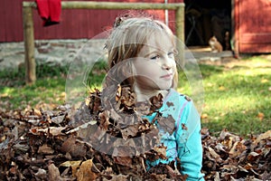 Girl sits up from hiding in leaves