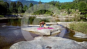 Girl sits in yoga position against pictorial river with rapids