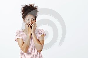 Girl sitting alone scared hearing sounds. Portrait of afraid timid and insecure woman with curly hair in striped t-shirt