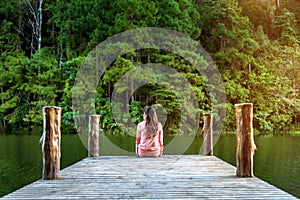 Girl sitting alone on a the wooden bridge on the lake. Pang Ung, Thailand