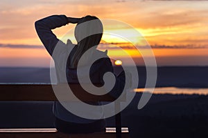 Girl sitting on a banch at sunset