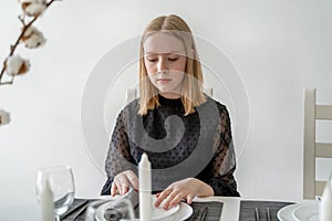 Girl sitting at the banquet table with dishes, looking away from camera, waiting fot guests.