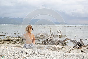 Girl sitting on the beach, looking at the horizon