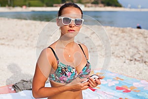 Girl sitting on the beach near see and using phone