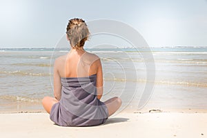 Girl sitting at the beach watching into the horizon