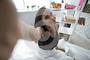 Girl sitting on bed and reaches out to camera