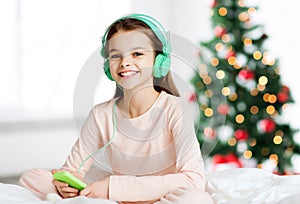 Girl sitting on bed with smartphone and headphones