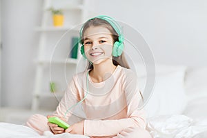 Girl sitting on bed with smartphone and headphones