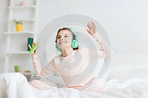 Girl sitting on bed with smartphone and headphones