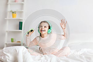 Girl sitting on bed with smartphone and headphones