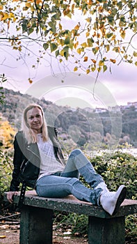 Girl sitting on a bench in the autumn park near the lake