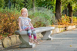 Girl sitting on bench in city park