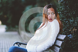 Girl sitting on bench in the city park in cold weather