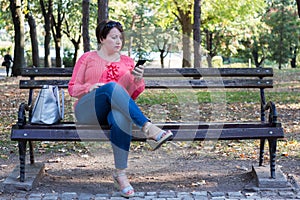 Girl Sitting on the Bench in a Park and Using Cellphone