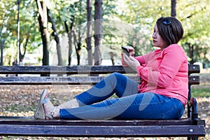 Girl Sitting on the Bench in a Park and Using Cellphone