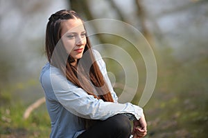 A girl sitting with a blue shirt, poses in the city park