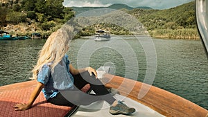 Girl sitting on boat and watching beautiful nature scene on Dalyan river. Mugla, Turkey.