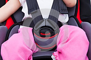 Girl sitting at carseat and fasten seat belt