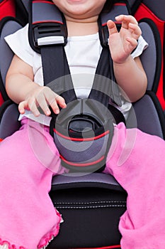 Girl sitting at carseat and fasten seat belt