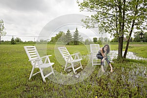 Girl Sitting on Chair in Rain Soaked Yard