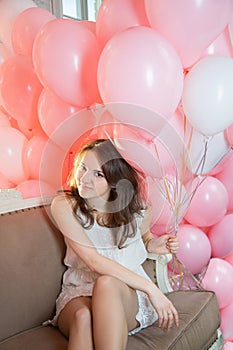 Girl sitting on the couch with lots of balloons