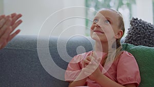 Girl sitting on couch in room with grandmother. Happy child clapping hands