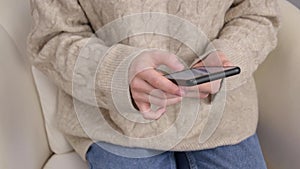 Girl is sitting on cozy home couch using modern smart phone device