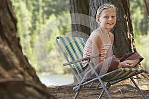 Girl Sitting On Deckchair In Forest