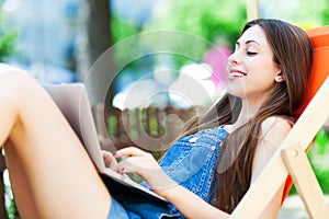 Girl sitting in deckchair using laptop