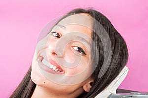 Girl sitting in dentist chair and showing big smile