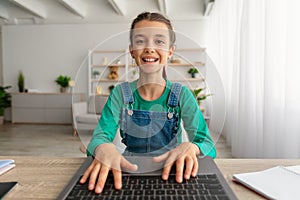 Girl sitting at desk, using laptop, typing on keyboard