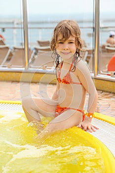 Girl sitting on edge of swimming pool